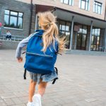 Young Girl With Blue Backpack Running to School