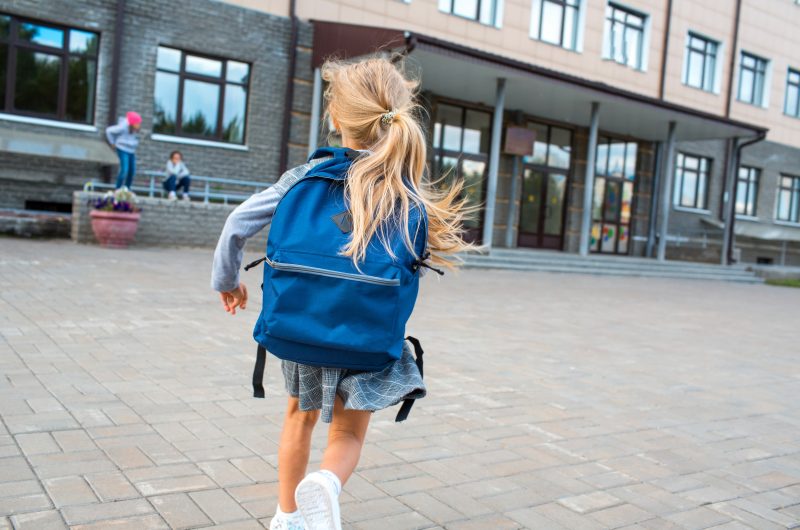 Young Girl With Blue Backpack Running to School